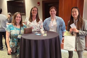 Four people standing at a cocktail table smiling